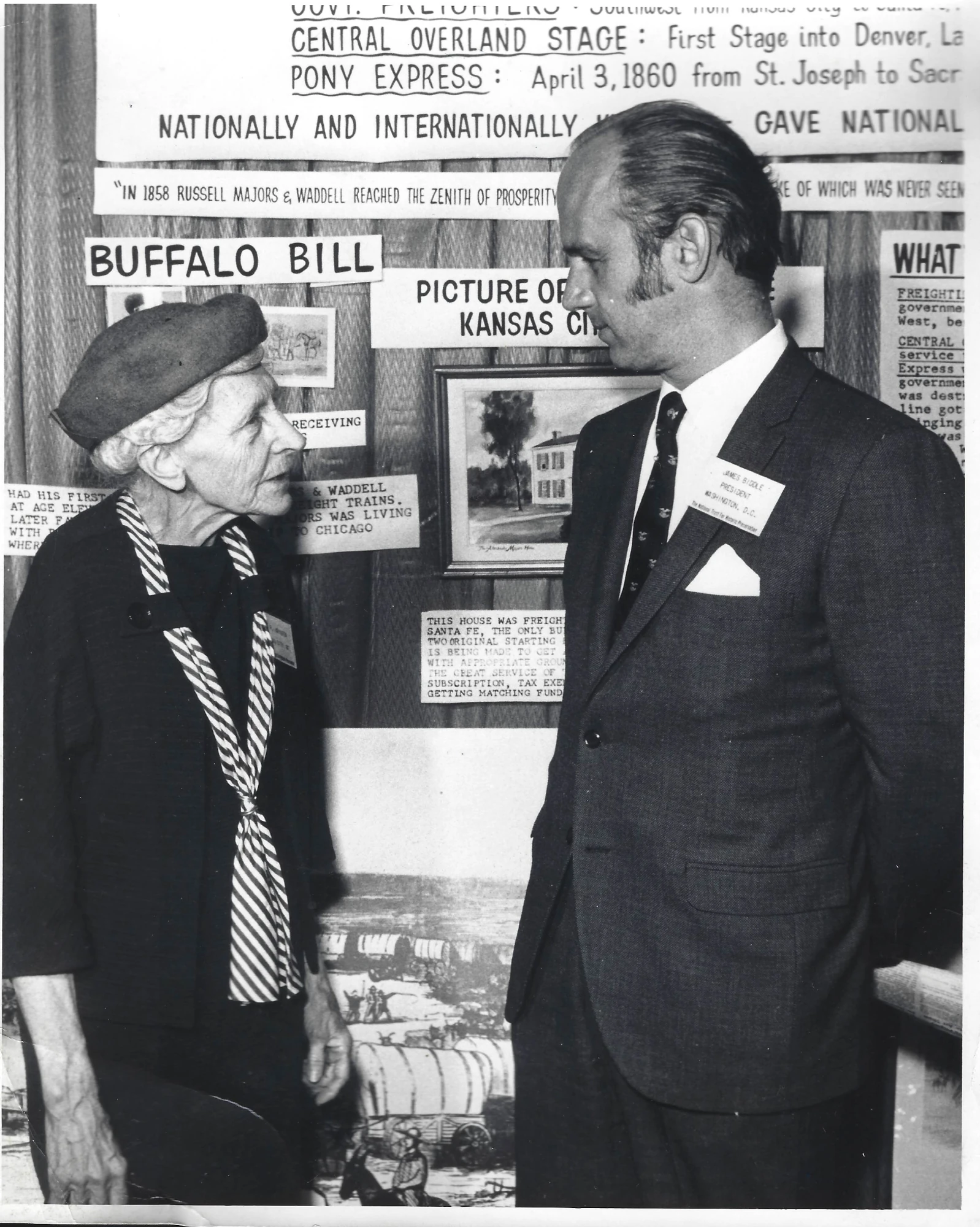 Louisa Johnston speaking to man in front of poster about Majors House